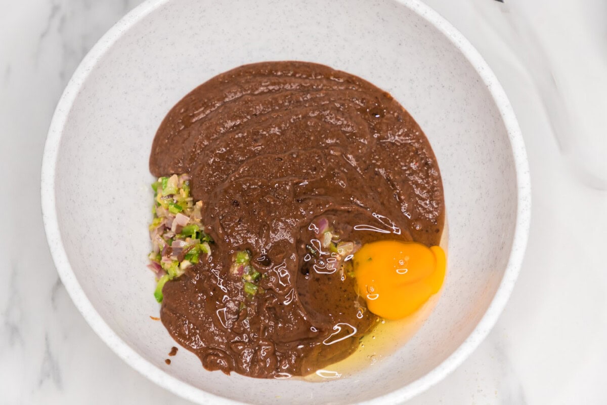 blended black bean mixture added to bowl with an egg, sauteed veggies, and whole black beans