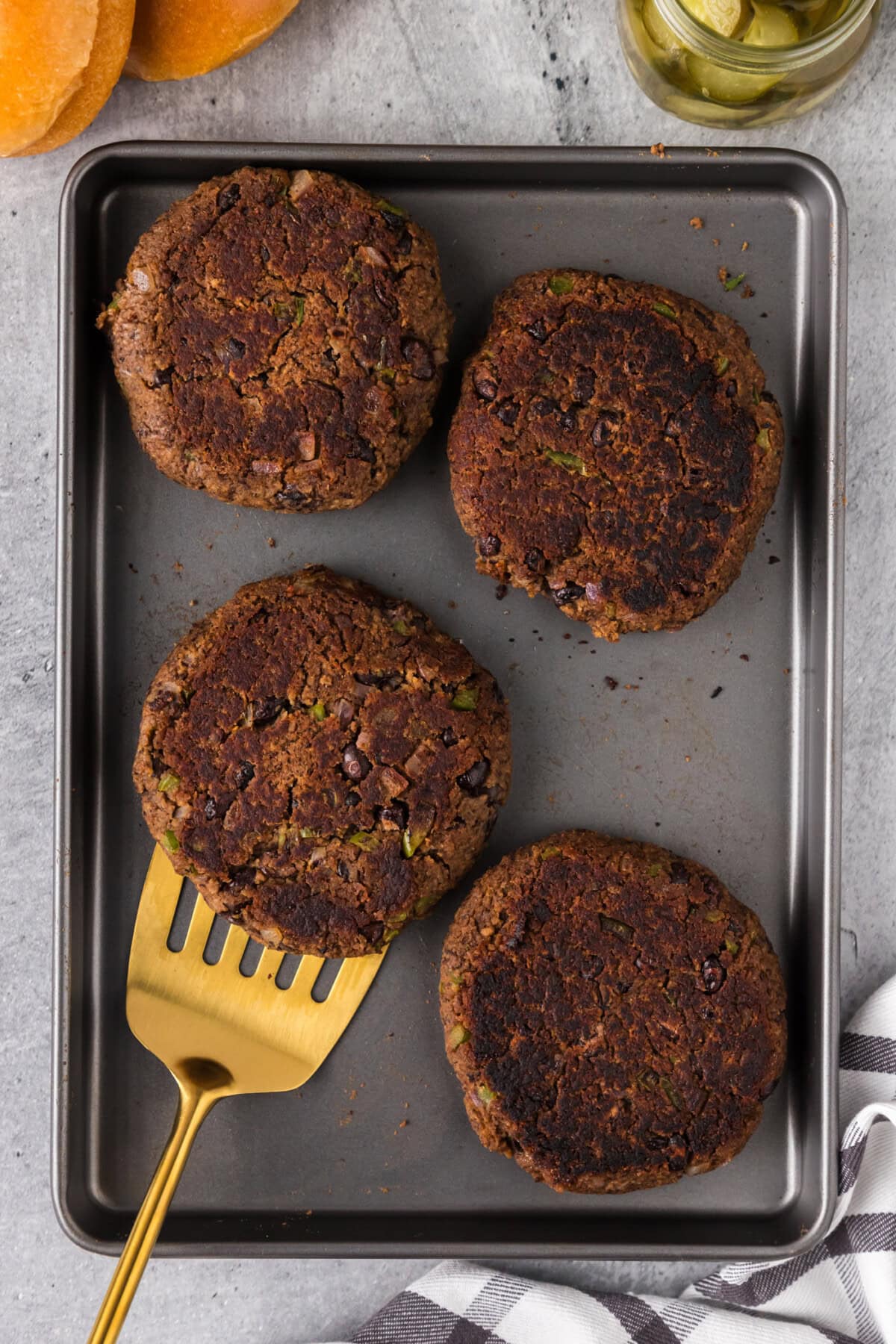 Four Black Bean Burger patties on a baking sheet with a spatula 