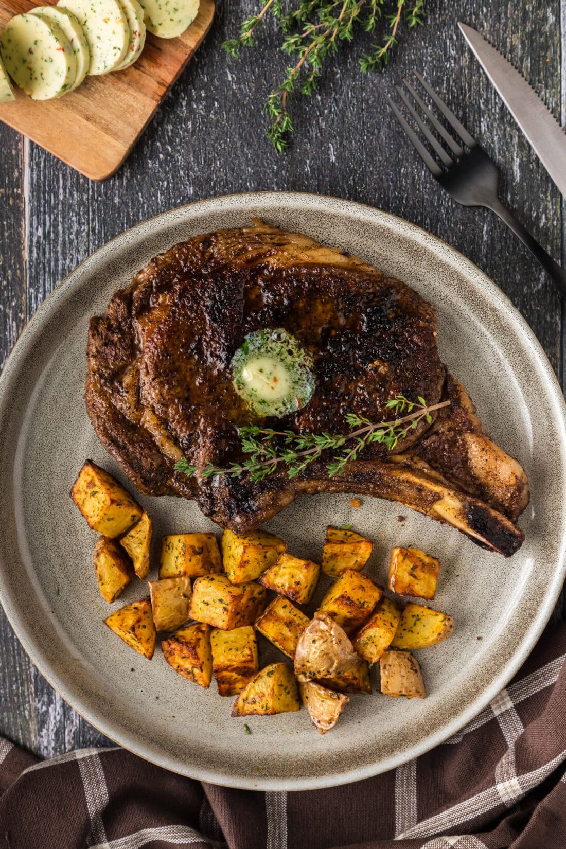 Bone in Ribeye on a plate with cubed potatoes