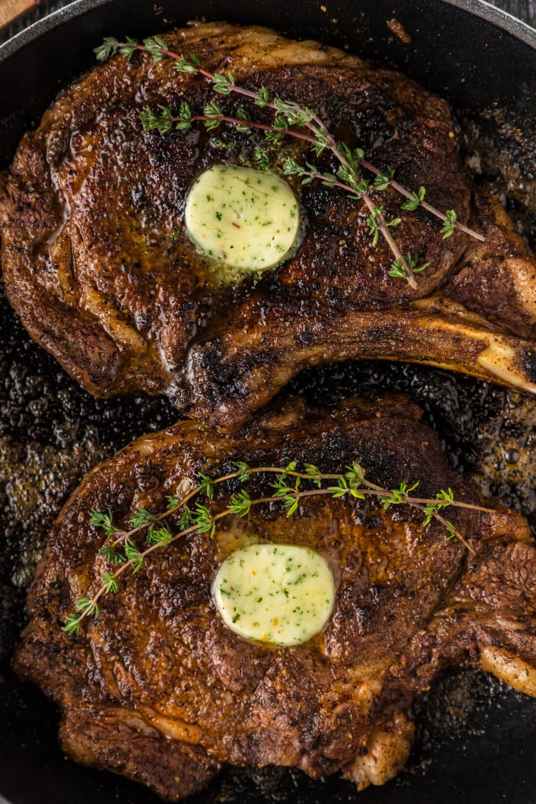 Close up photo of two Bone in Ribeyes in a skillet