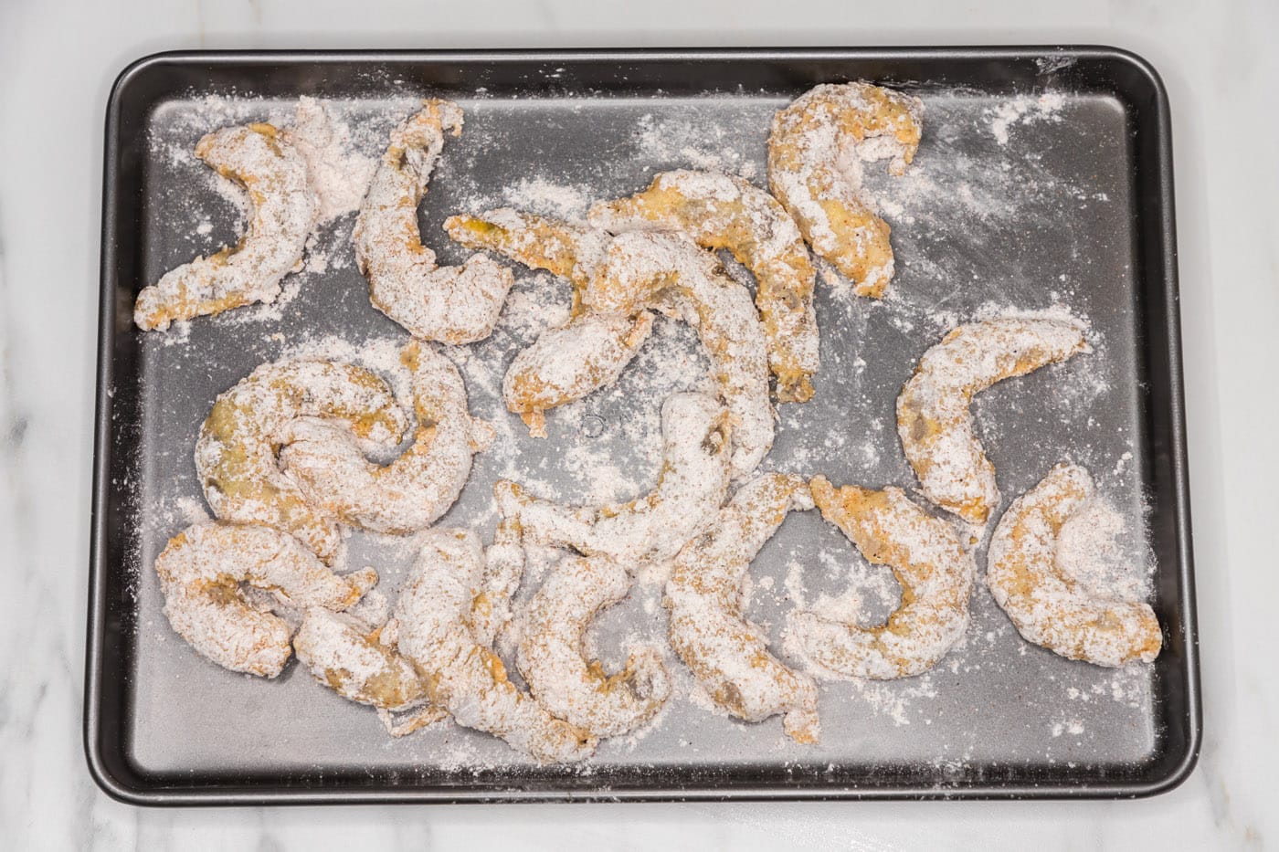 flour dredged shrimp on a baking sheet