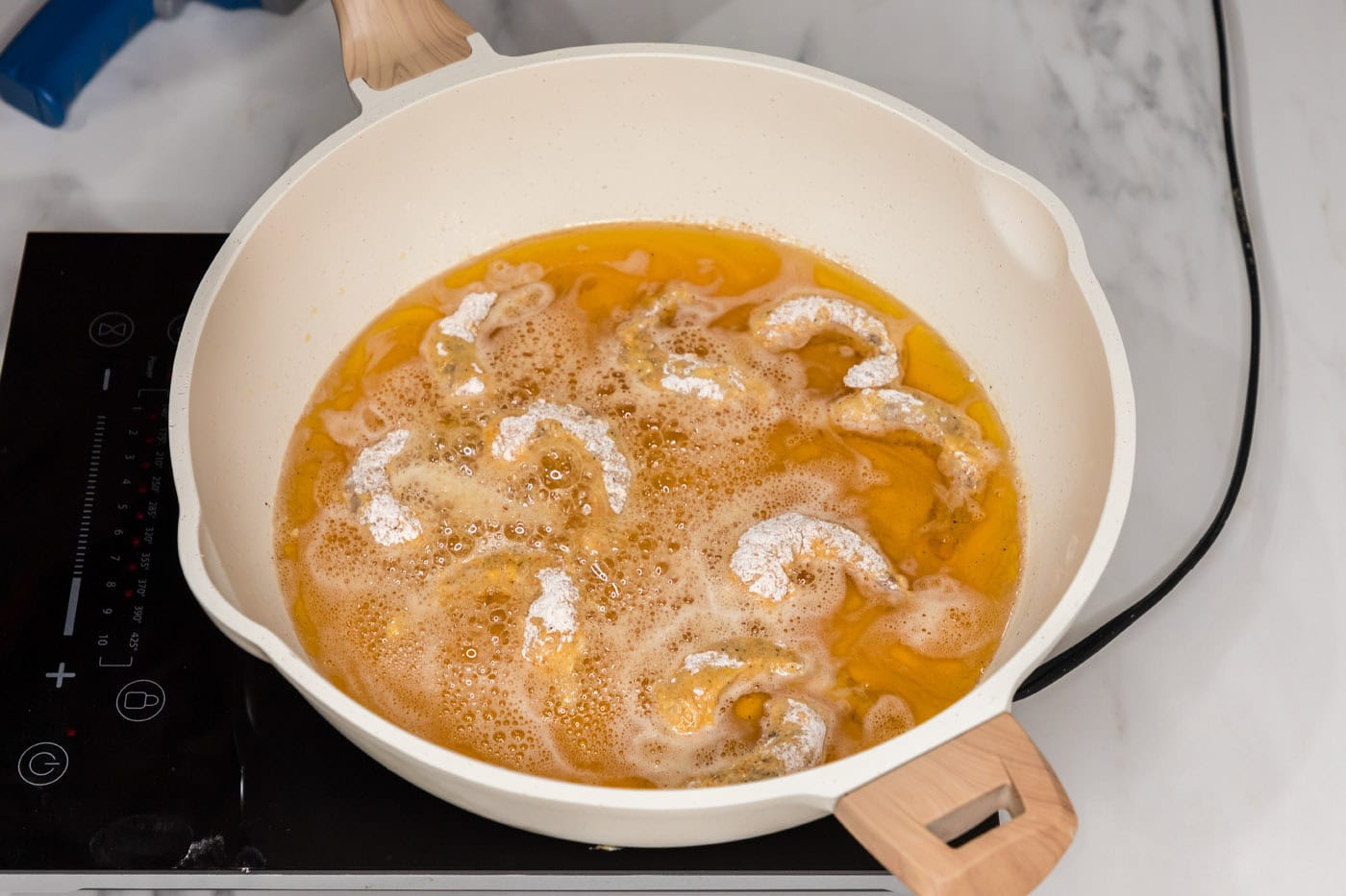 frying shrimp in oil in a skillet