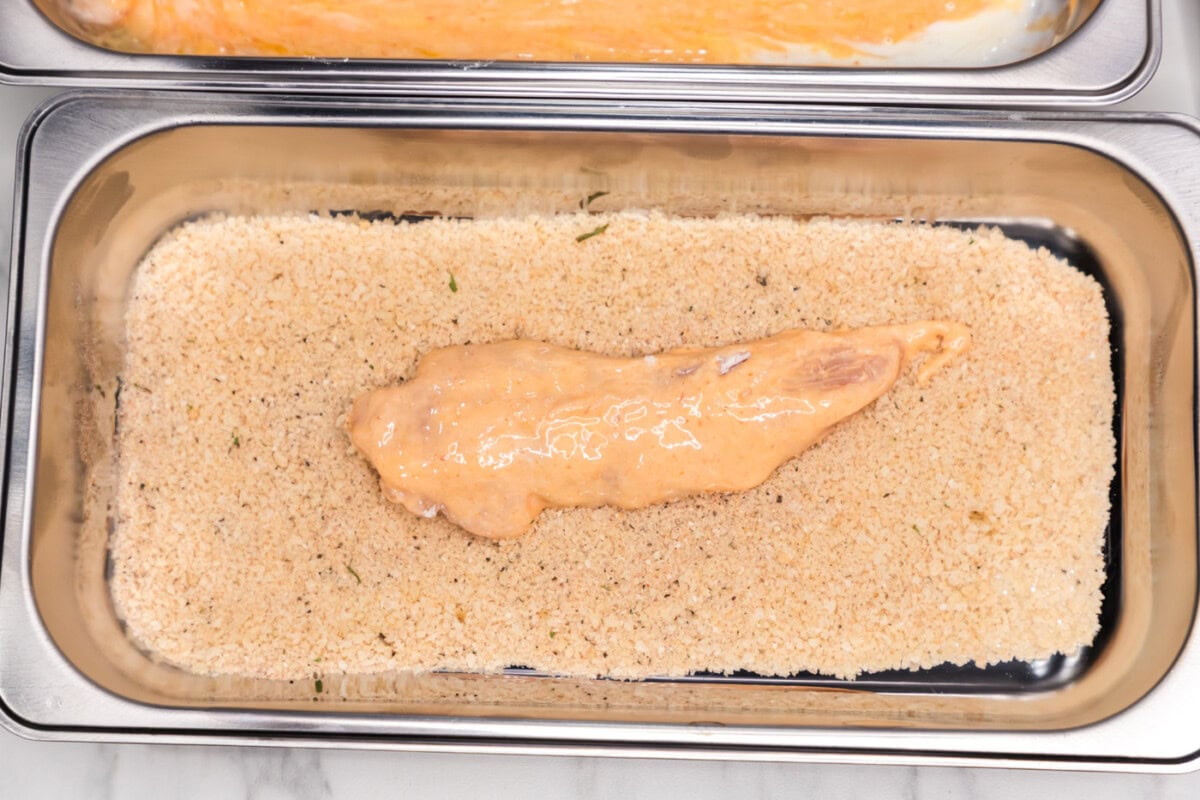 dredged buffalo chicken added to pan of breadcrumb mixture