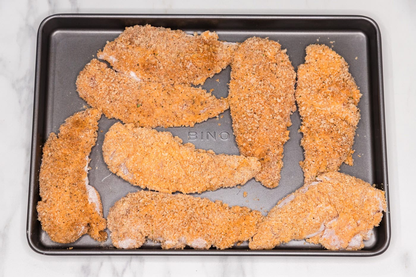 panko breadcrumb coated chicken tenders on a baking sheet