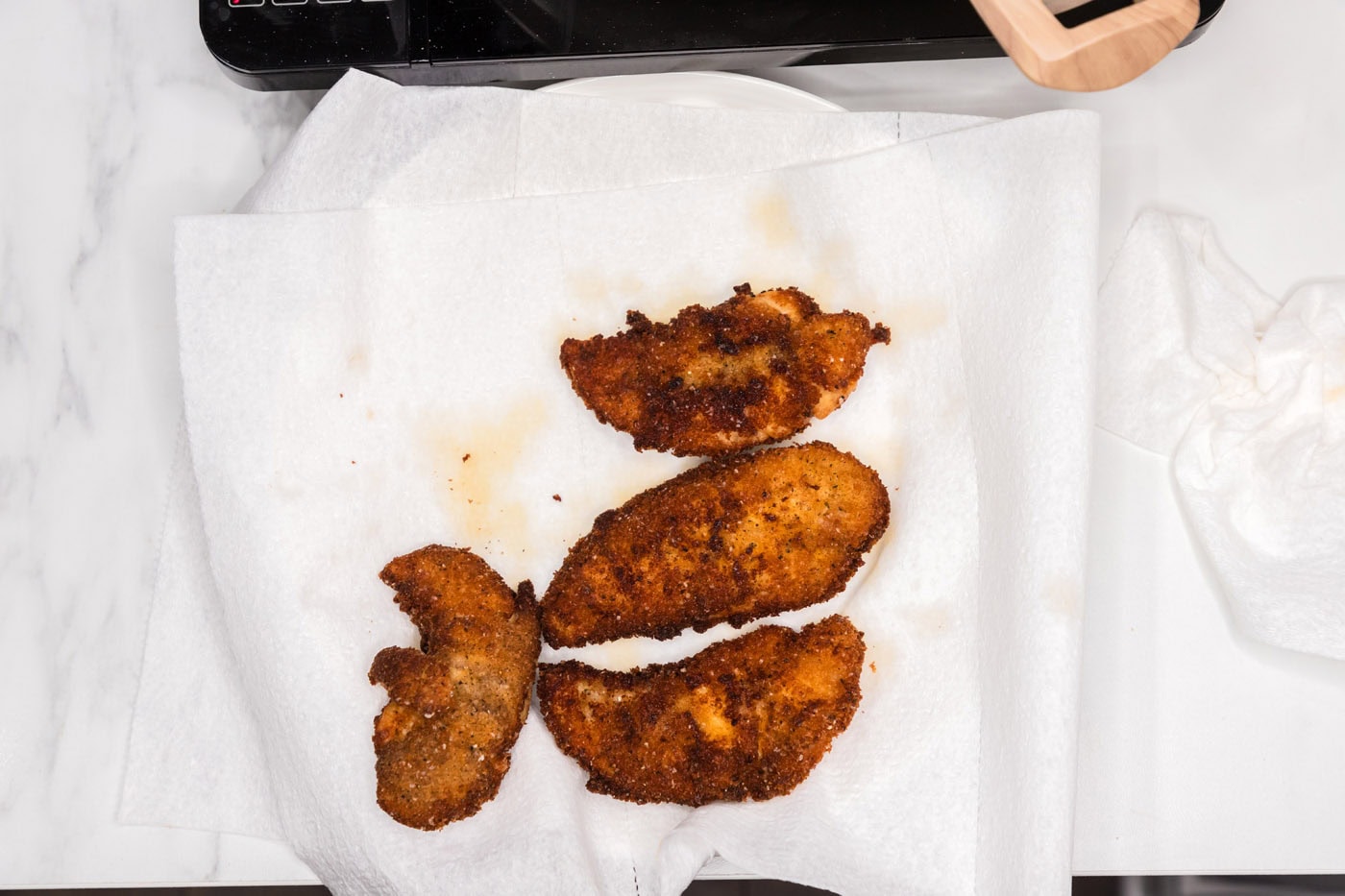 crispy fried chicken tenders draining on paper towels