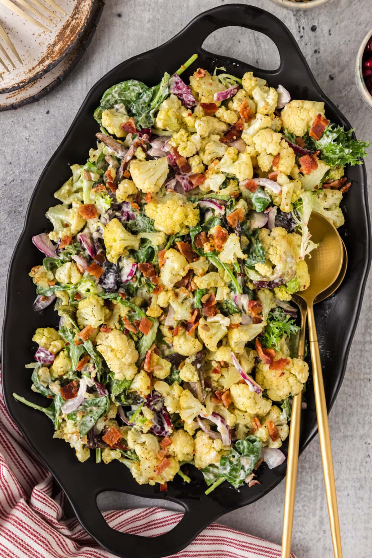 Cauliflower Salad on a black platter with two serving spoons