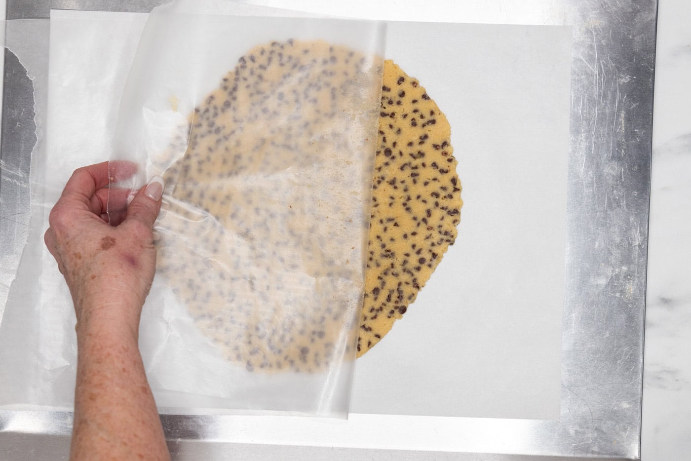 peeling parchment paper off rolled out cookie dough
