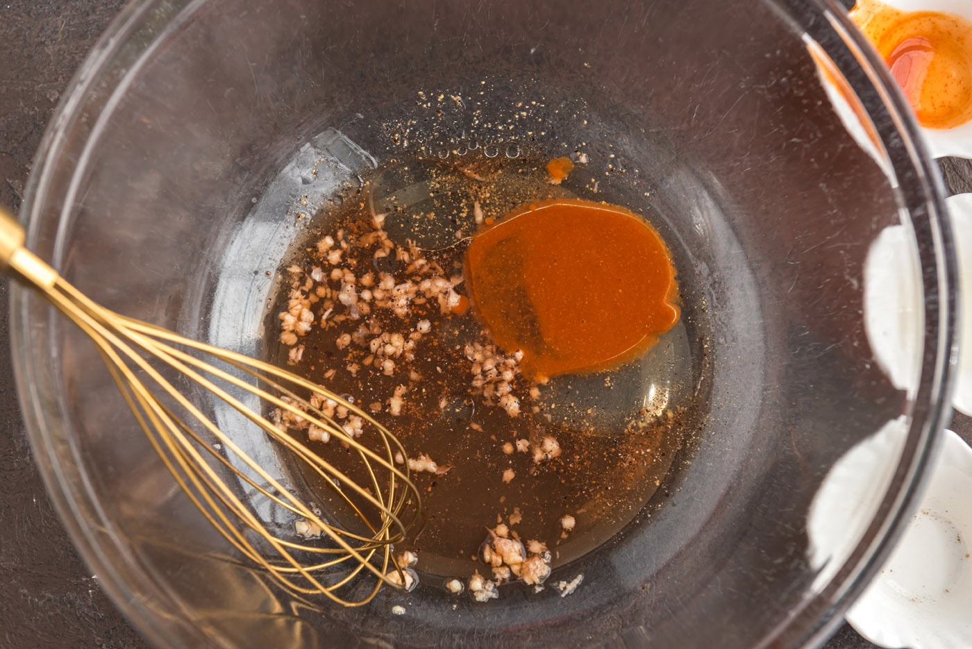 whisking hot sauce, oil, vinegar, and garlic in a bowl