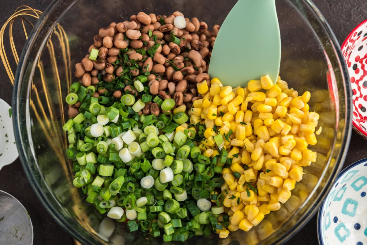 adding green onion to bowl of cowboy caviar