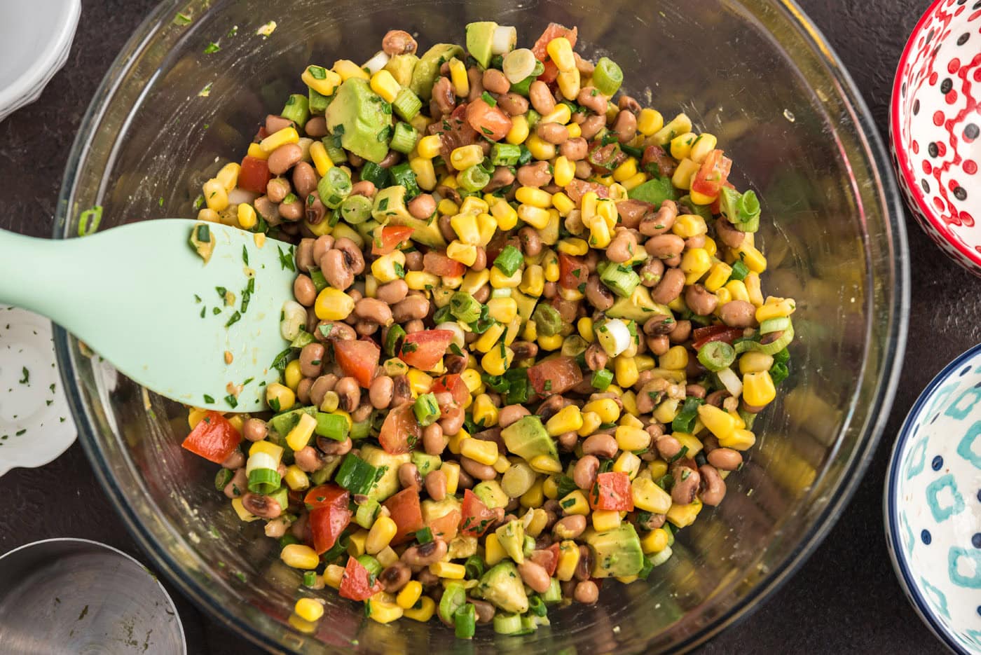 mixed cowboy caviar in a bowl with a rubber spatula