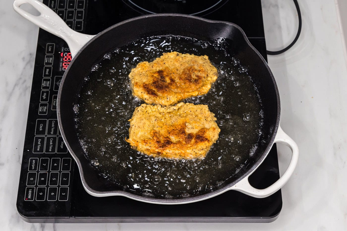 fried chicken burgers in a skillet with oil
