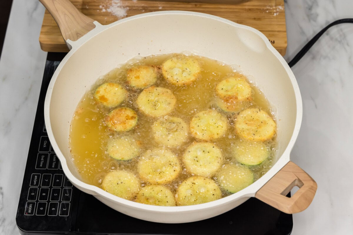 skillet with oil frying yellow squash and zucchini
