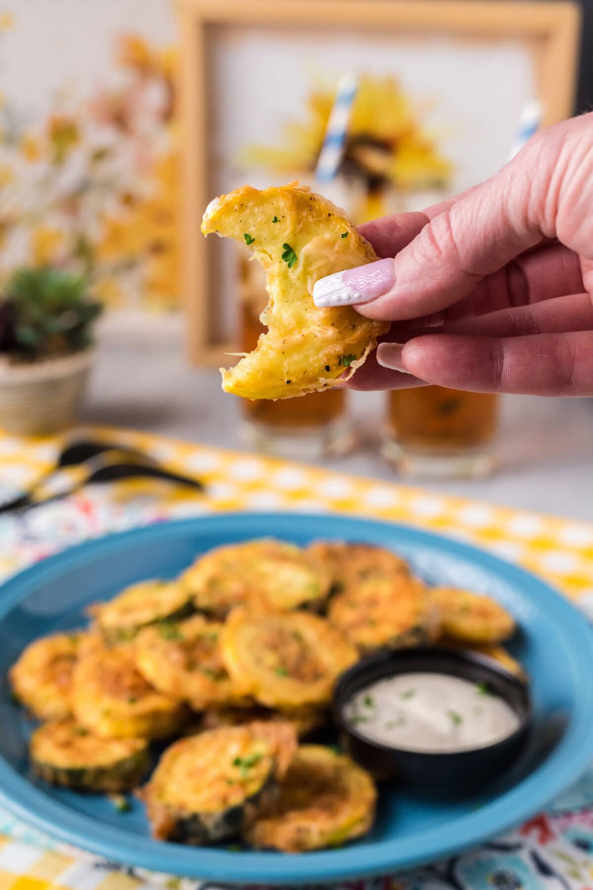 Hand holding up a piece of Fried Squash with a bite taken out