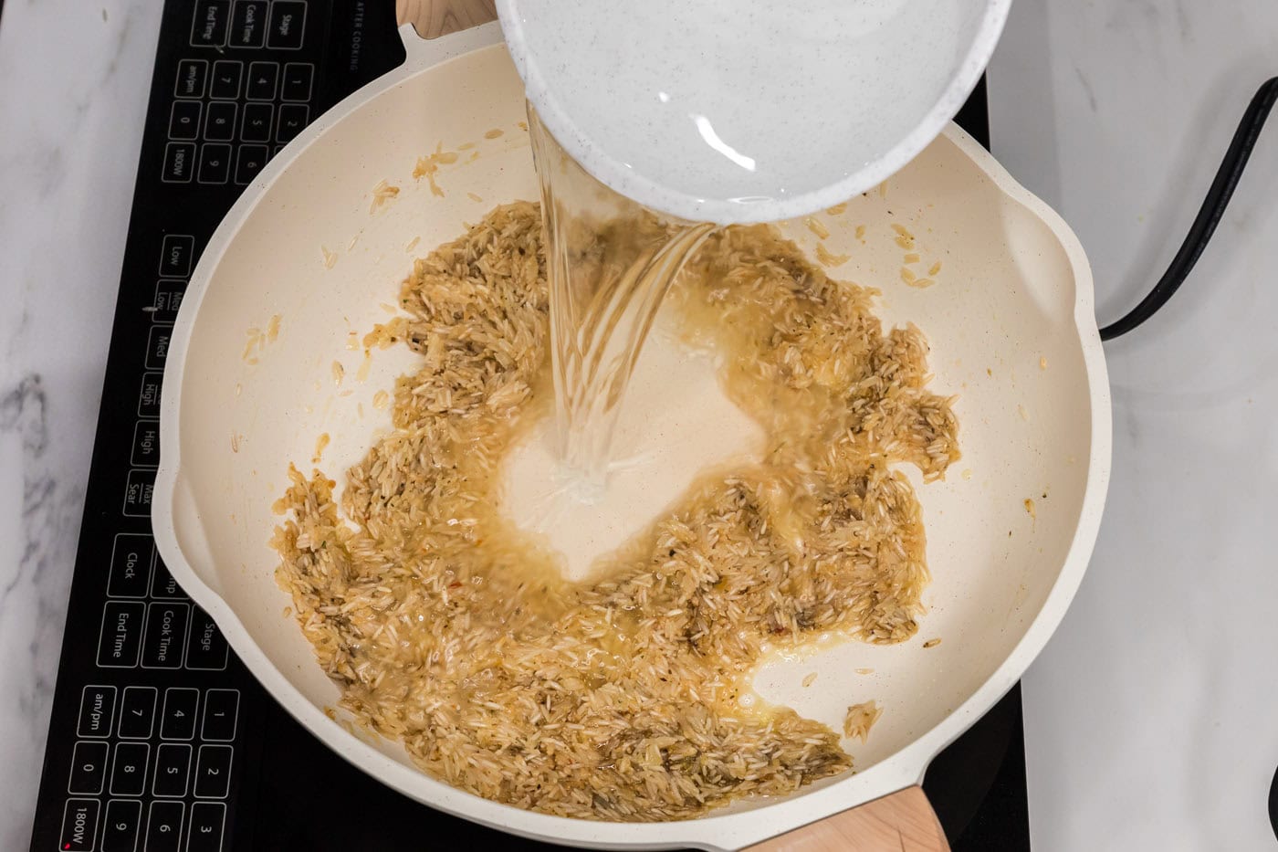 pouring water in skillet with garlic butter rice