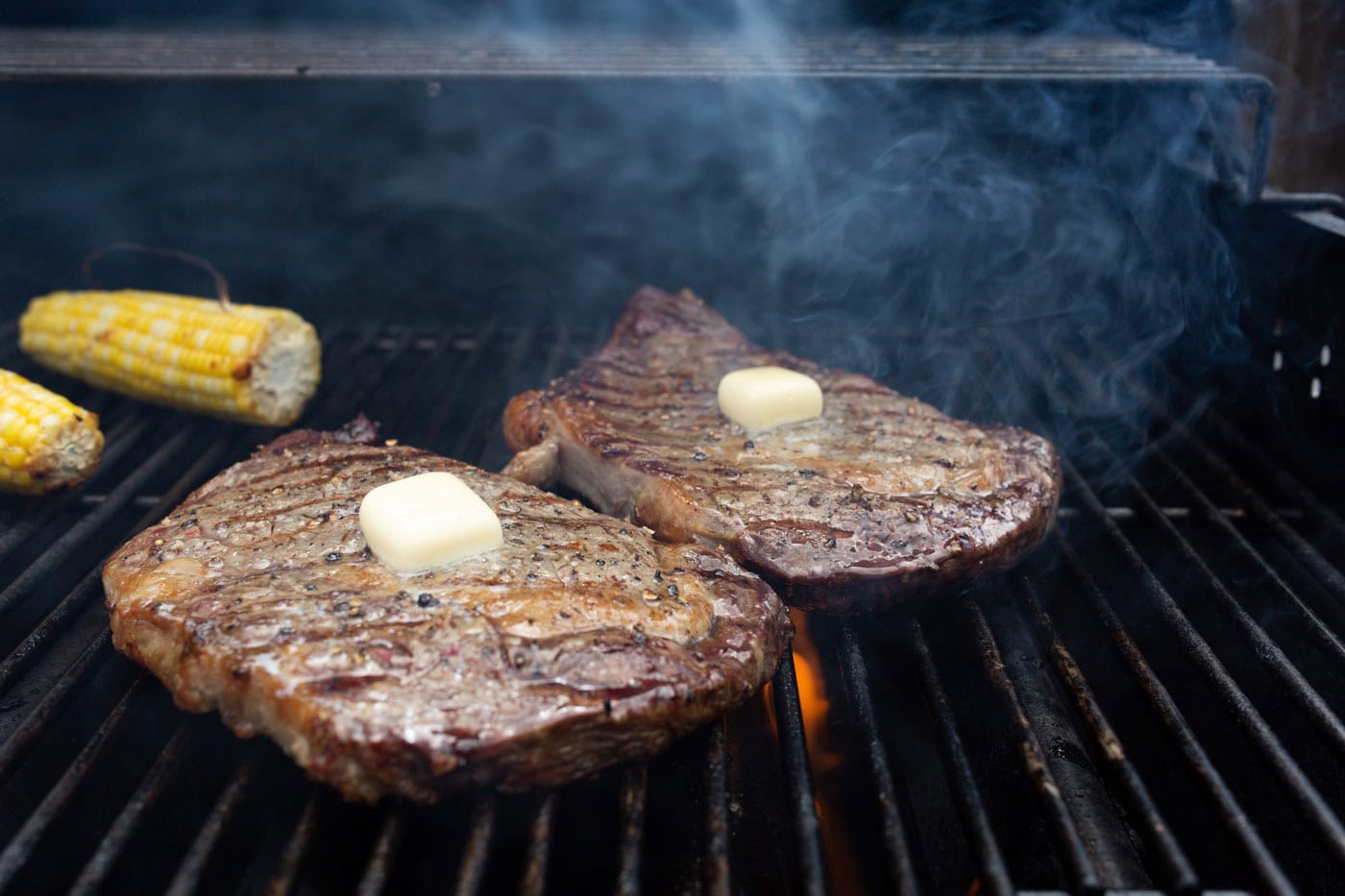 pats of butter on grilled new york strips steaks