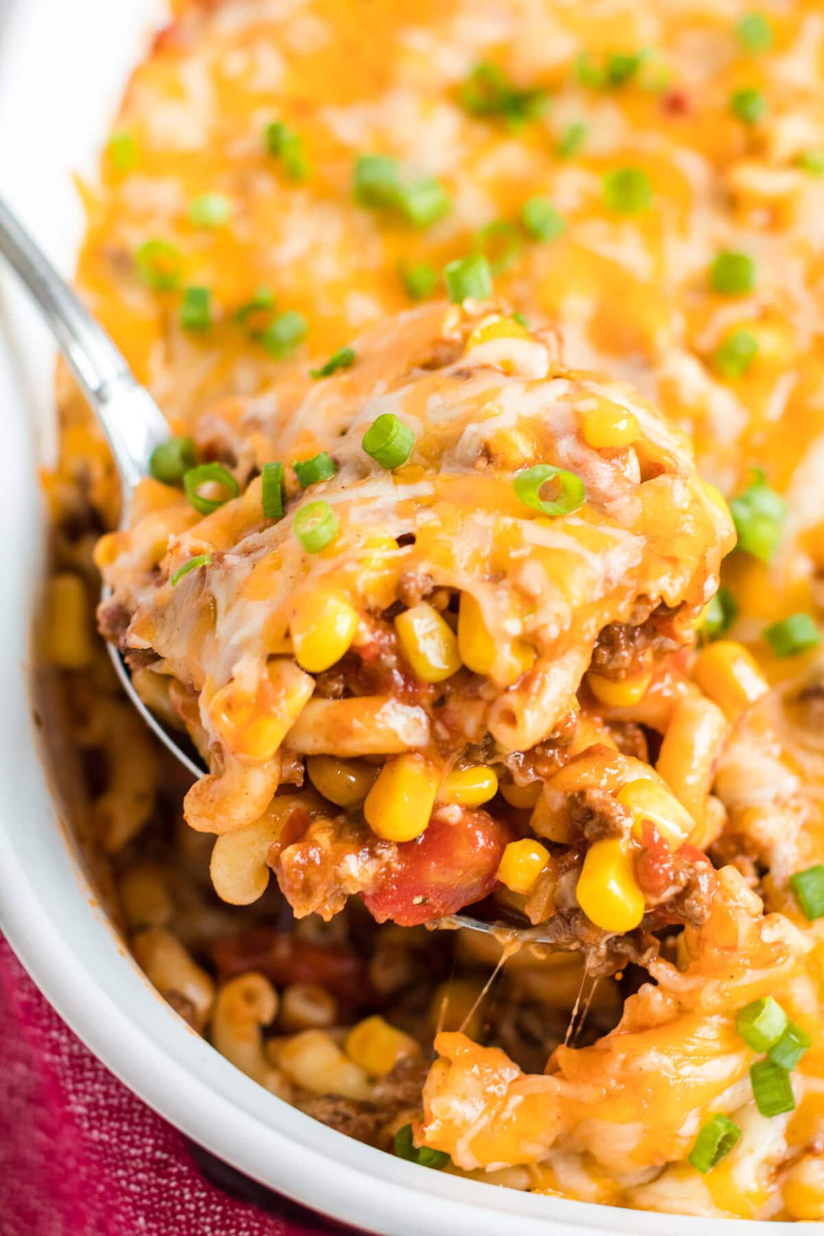 spoon lifting out ground beef casserole from dish