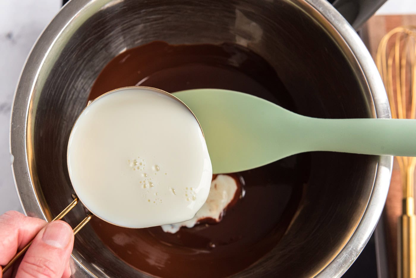 whisking milk into melted chocolate in a large bowl