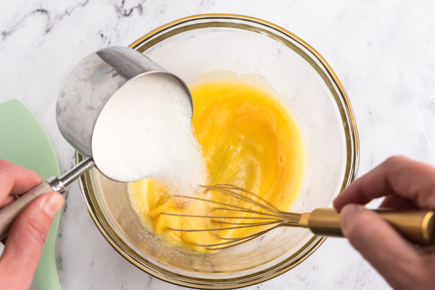 whisking sugar into eggs in a bowl