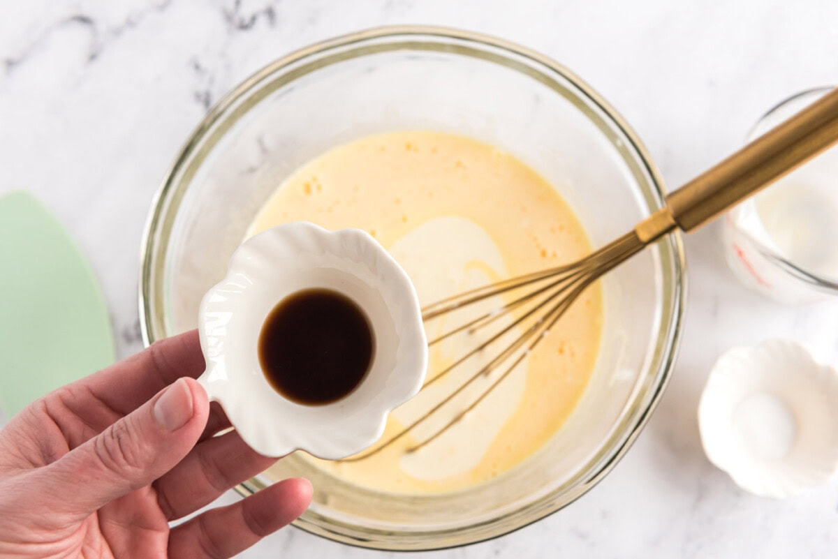 adding vanilla to whisked eggs, sugar, and heavy cream mixture