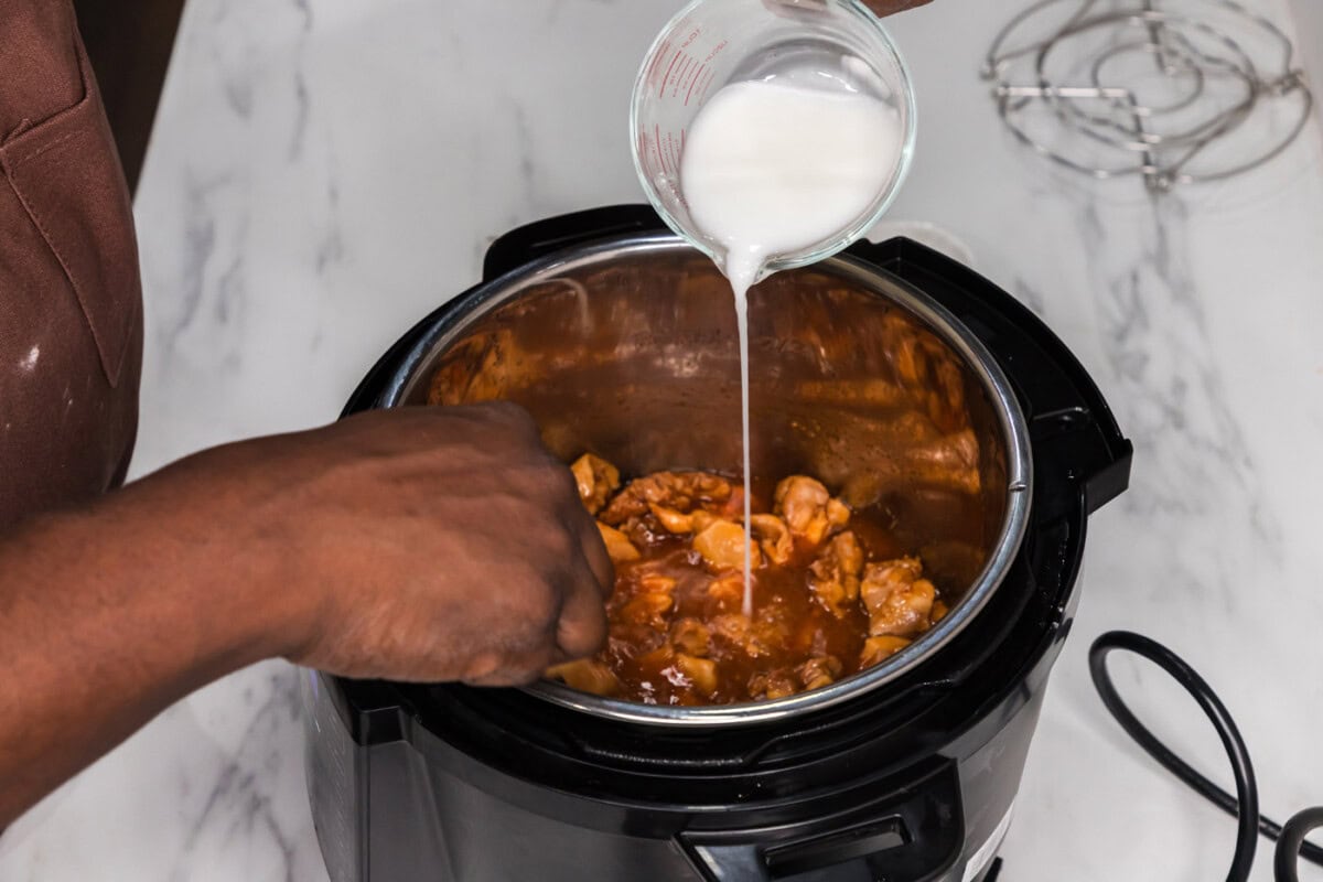 pouring cornstarch slurry into instant pot trivet with bourbon chicken