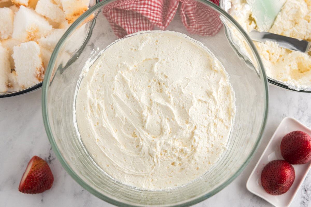 layer of whipped cream cheese on top of angel food cake in a trifle dish