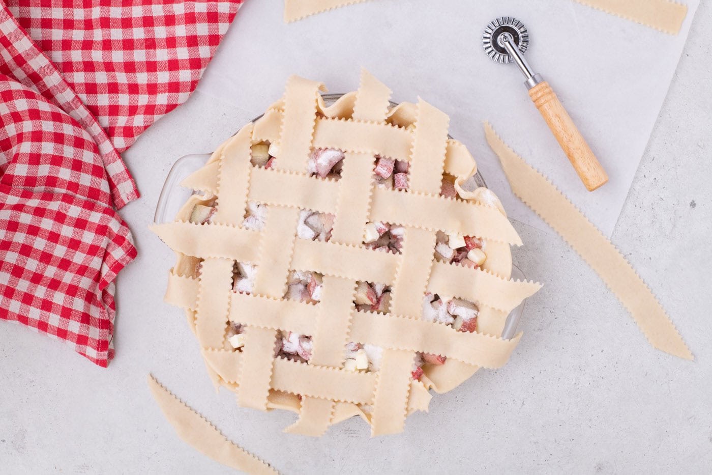 weaving pie crust strips into a lattice top over rhubarb pie