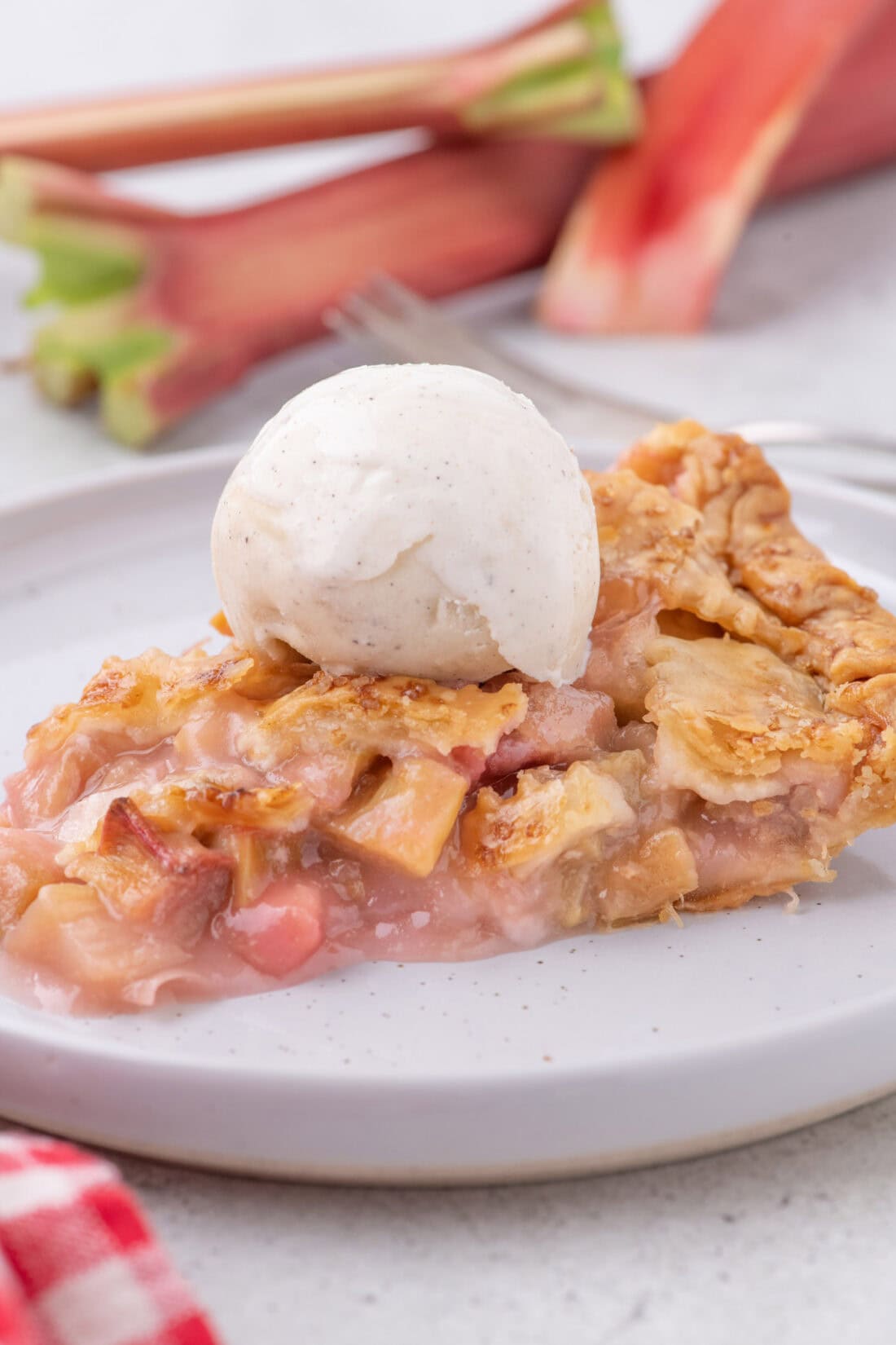 Slice of Rhubarb Pie on a plate topped with ice cream