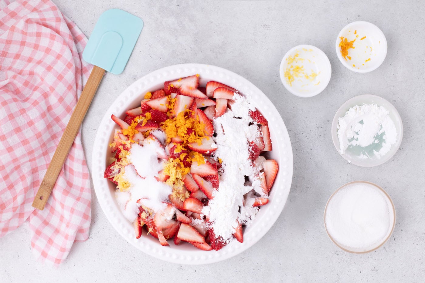 sugar, orange zest, and lemon zest over sliced strawberries