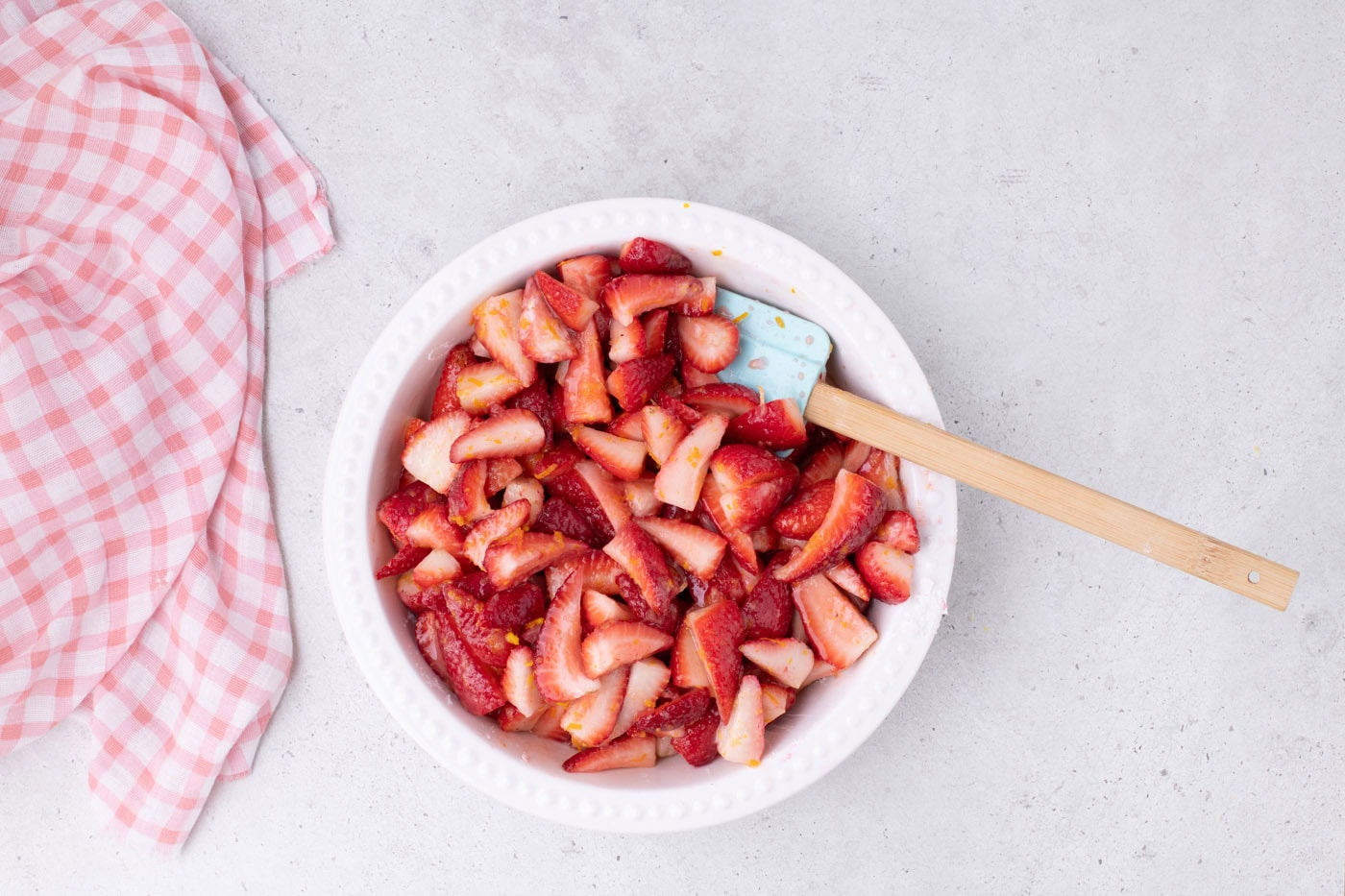 sliced strawberries in a bowl with sugar, cornstarch, and citrus zest