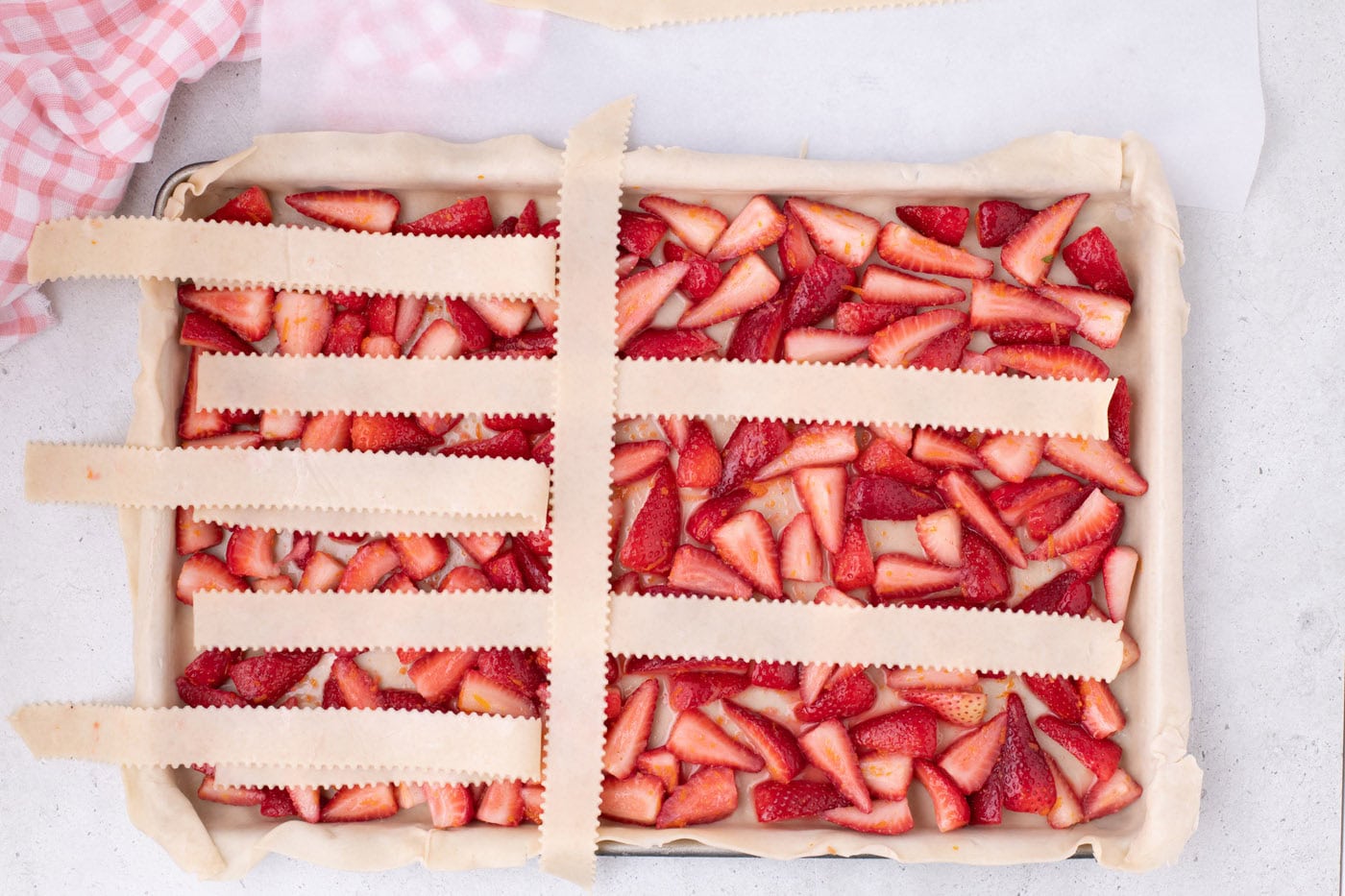 weaving pie crust into a lattice top over strawberries