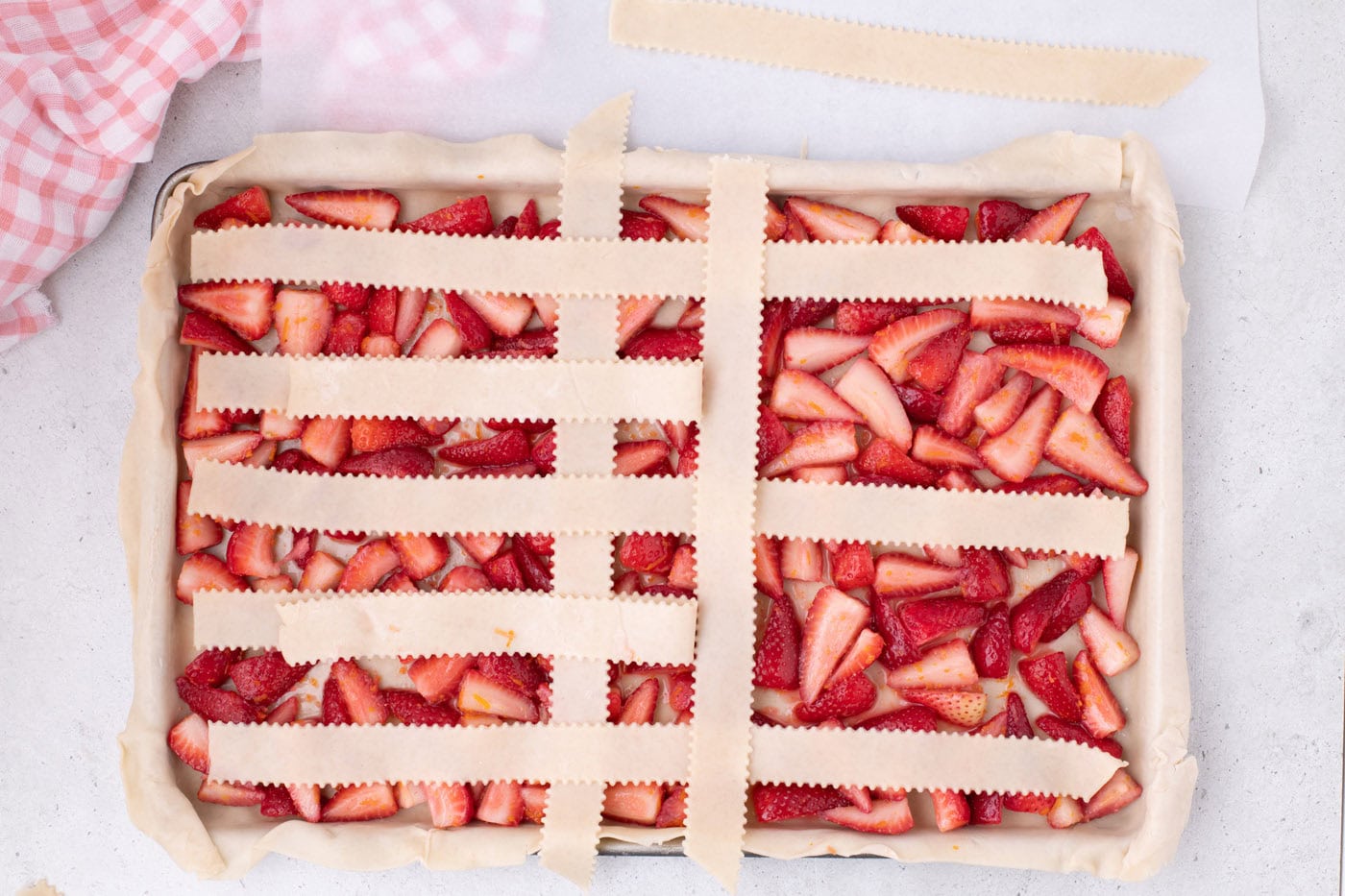 weaving pie crust into a lattice top over strawberries