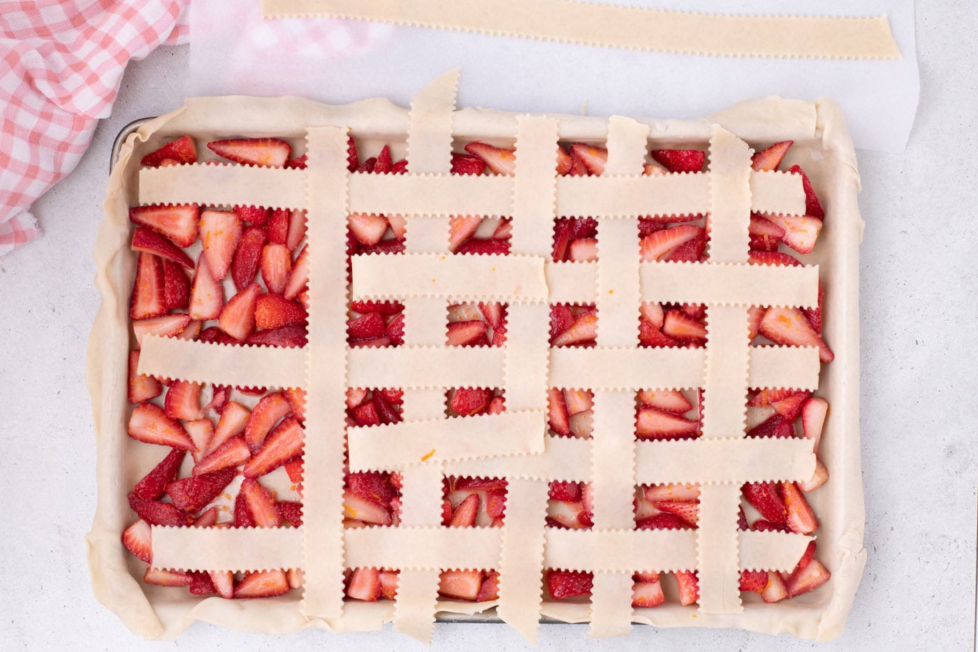 weaving pie crust into a lattice top over strawberries