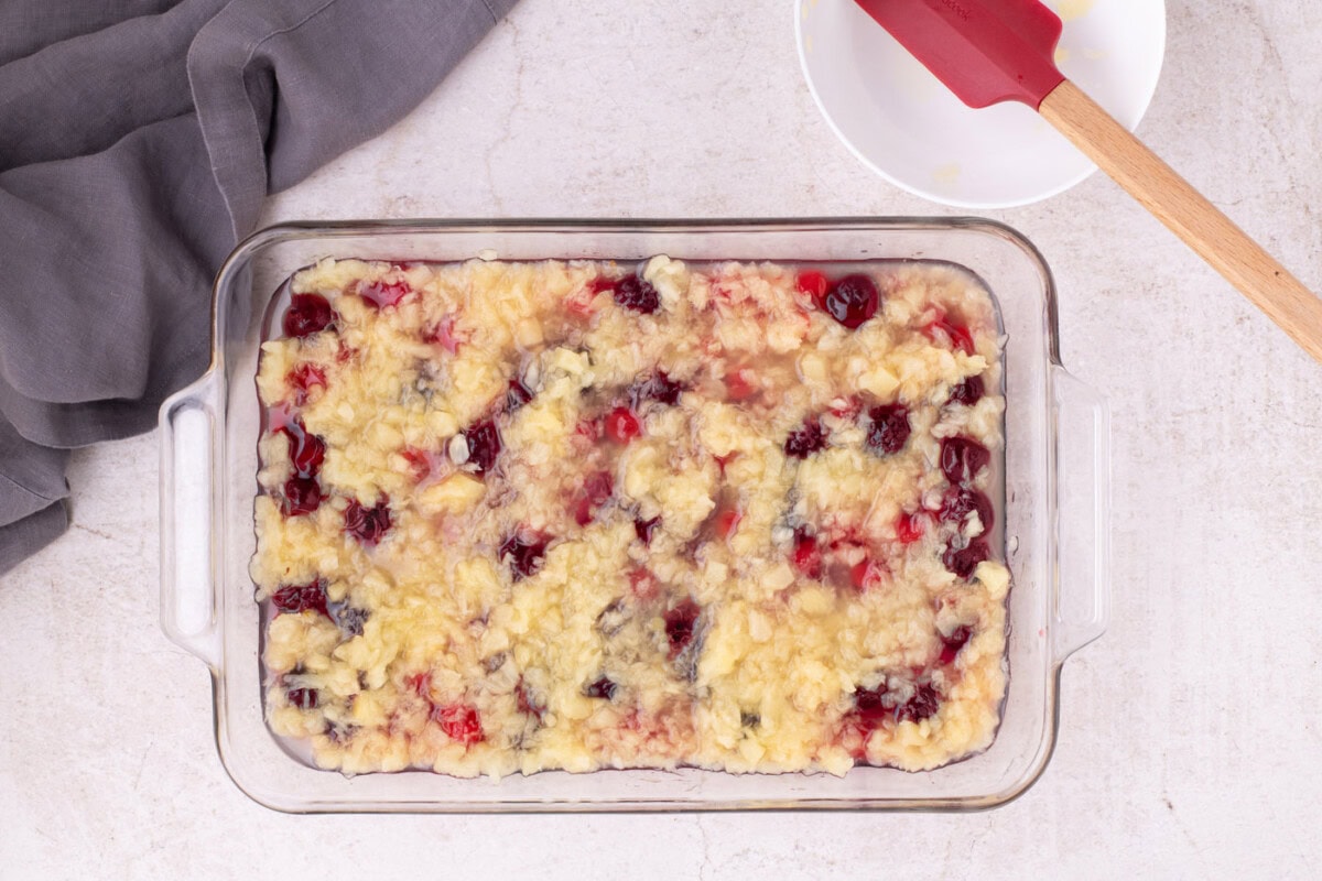 crushed pineapple poured over cherry pie filling in a baking dish