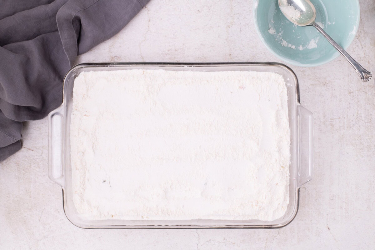 powdered cake mix over top of cherry pie filling and pineapple in a baking dish
