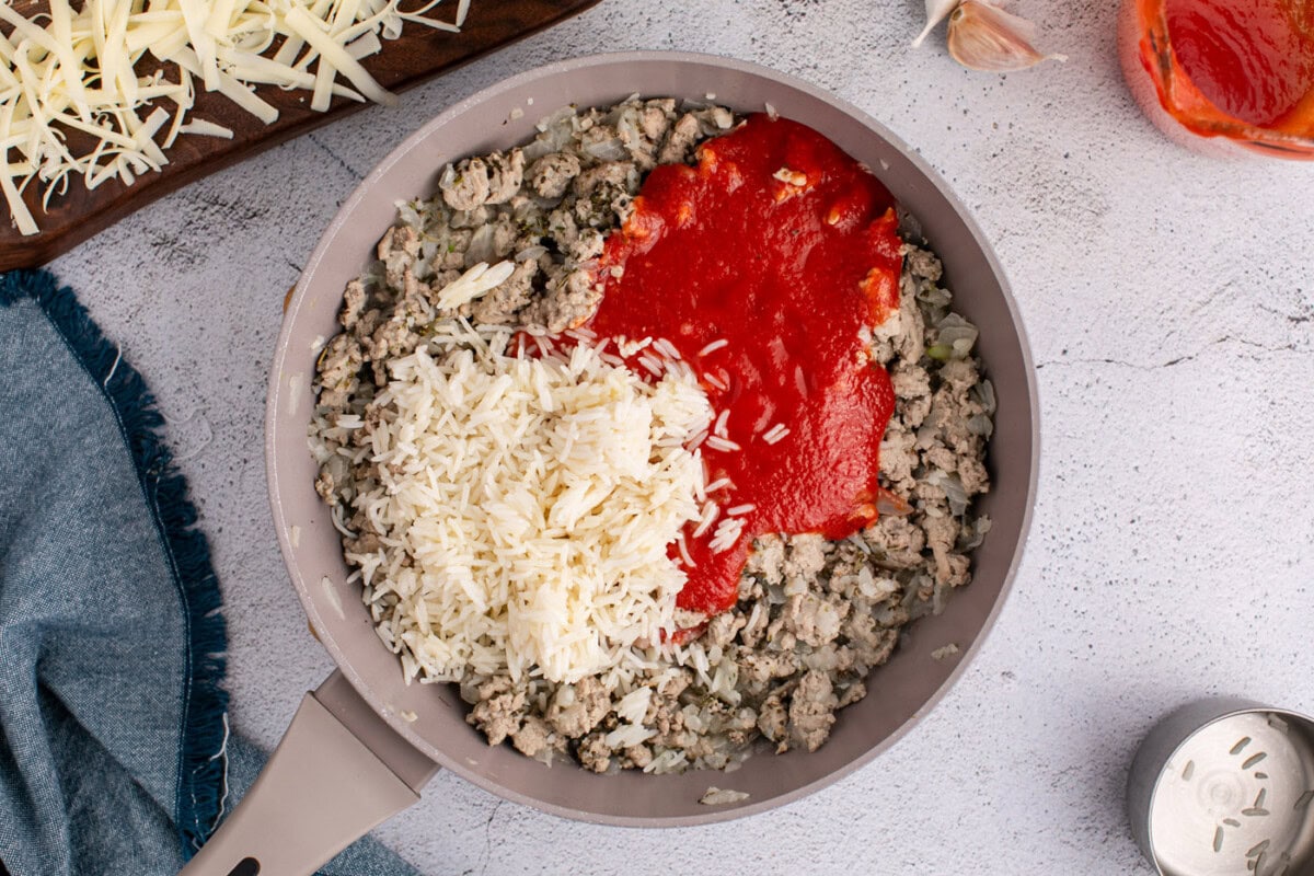 strained tomatoes and rice added to ground turkey mixture in a skillet