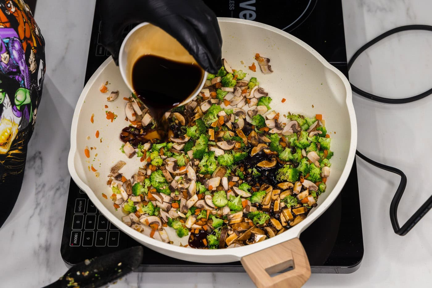 pouring soy sauce into skillet with chopped vegetables