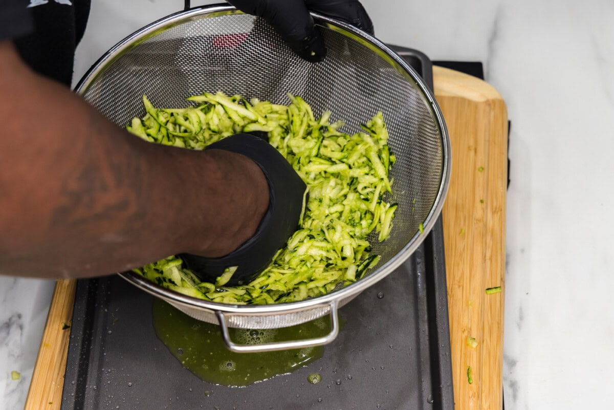 squeezing moisture out of zucchini in a colander