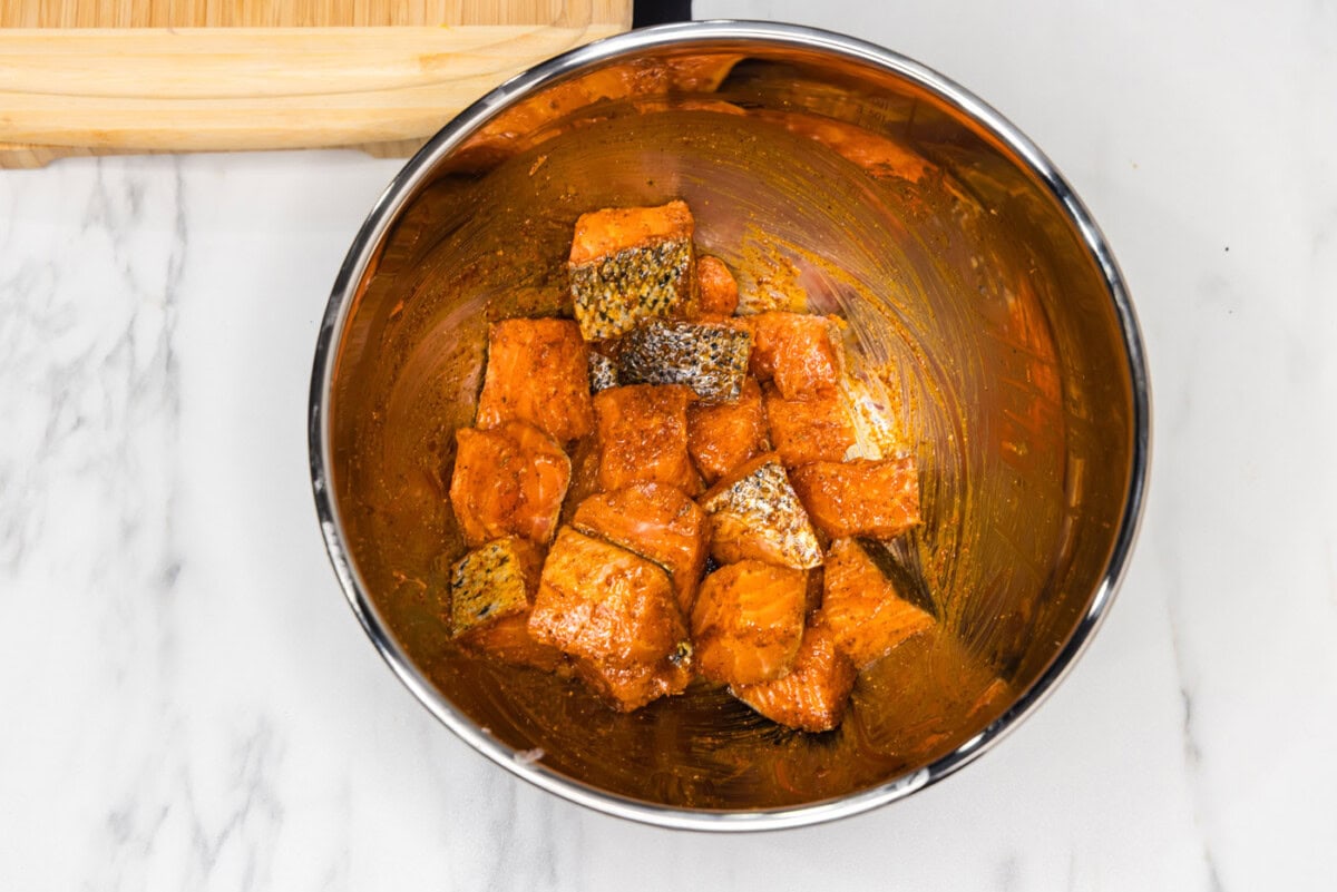 salmon bites tossed in a wet rub in a mixing bowl