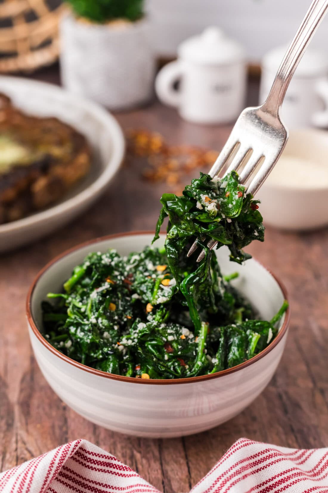 Forkful of Air Fryer Spinach being lifted out of a bowl of Air Fryer Spinach