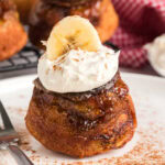 Close up photo of a Banana Upside Down Muffin topped with whipped cream and a banana slice