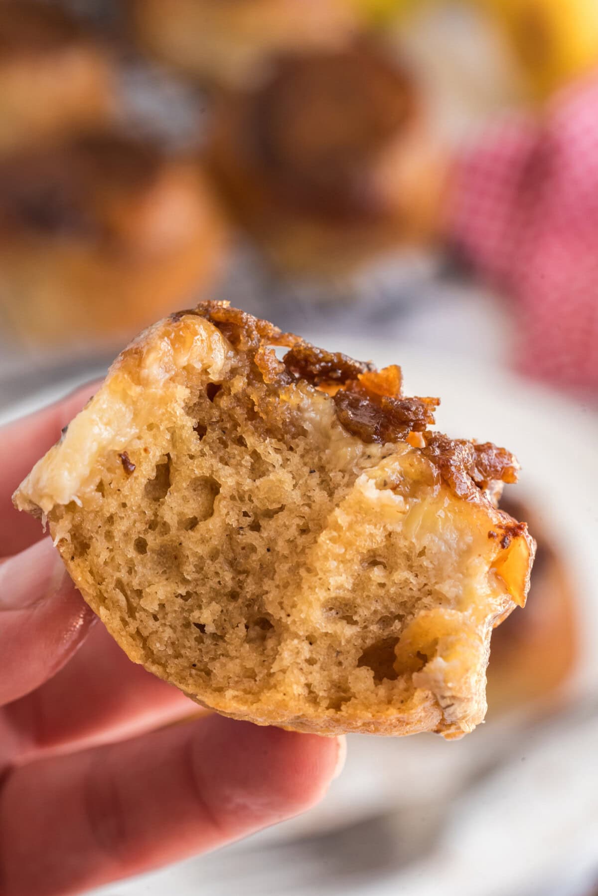 Hand holding up a Banana Upside Down Muffin with two bites taken out 