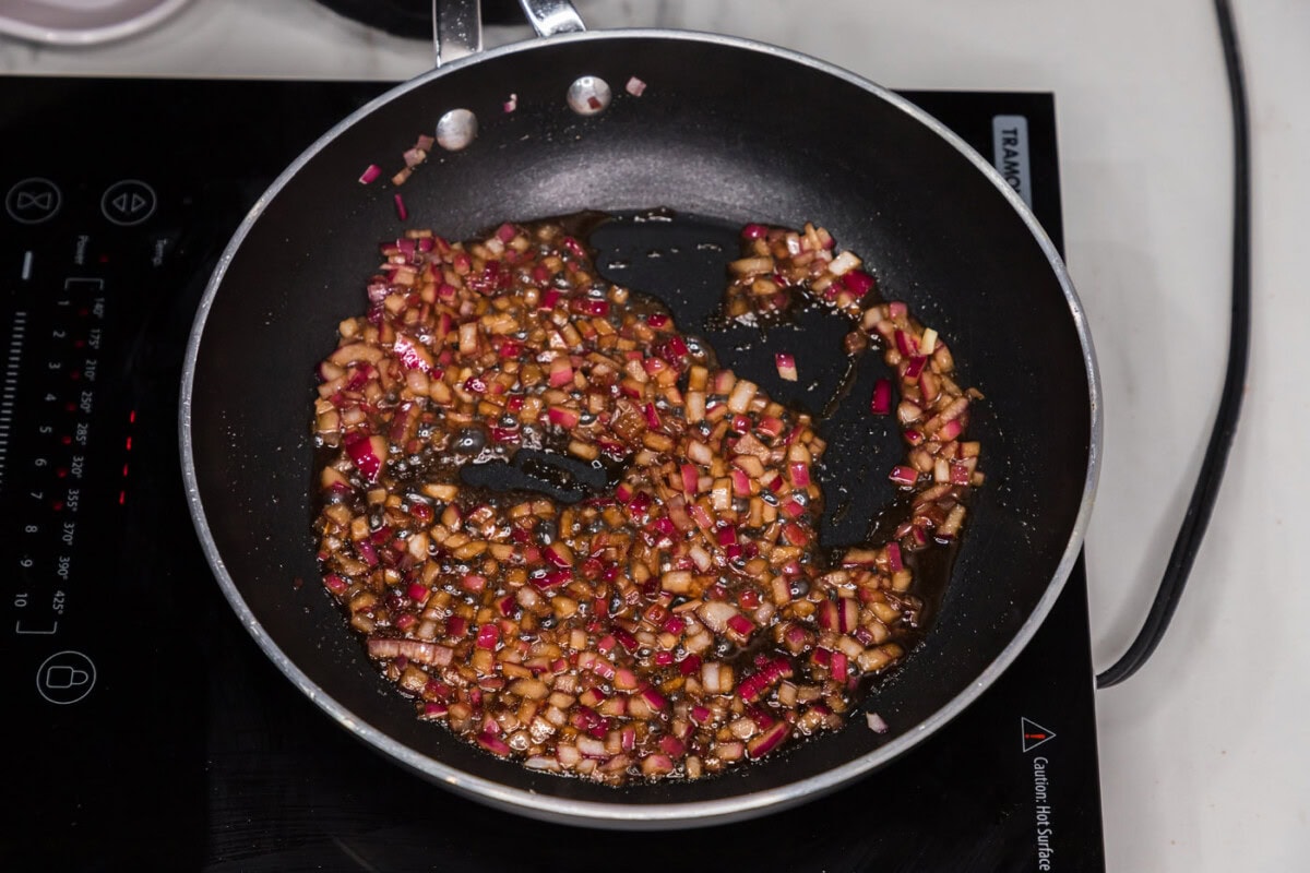 red onion sauteeing in olive oil in a skillet with liquid smoke and worcestershire sauce