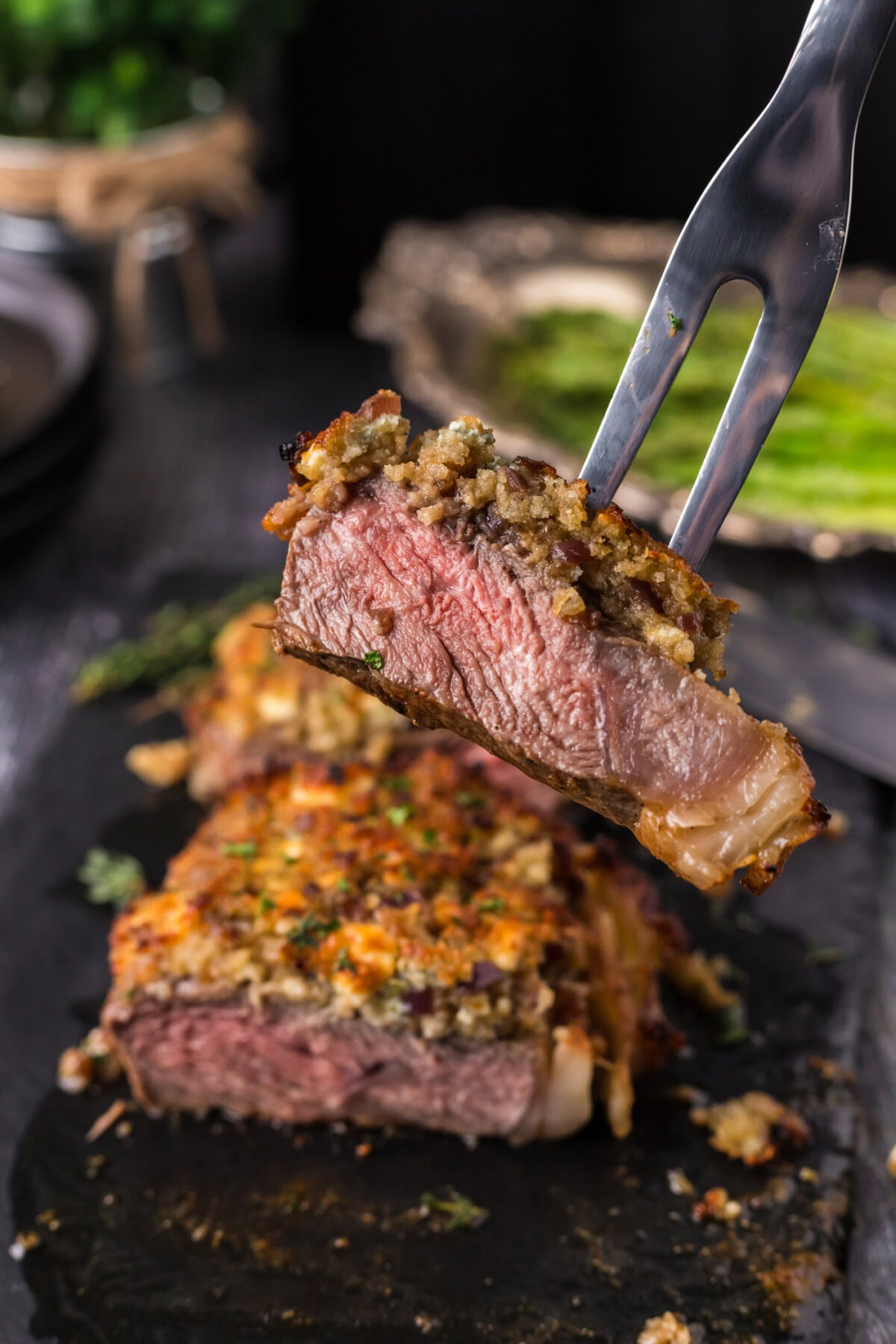 Meat fork lifting up a piece of Blue Cheese Crusted Steak