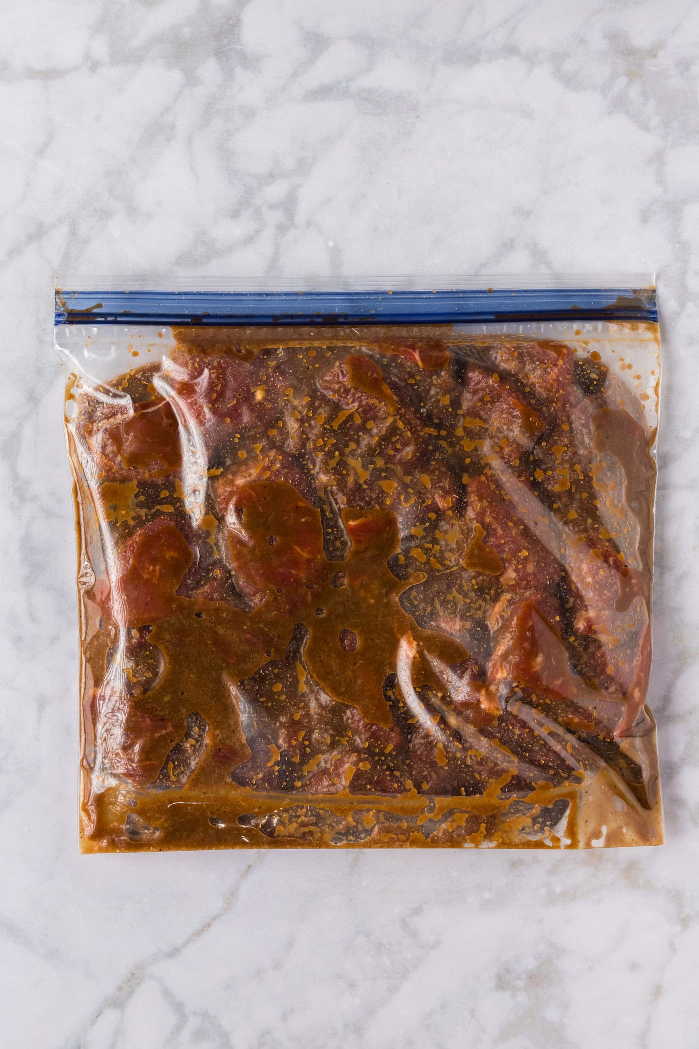 sliced steak in a ziptop bag with brown sugar bourbon marinade