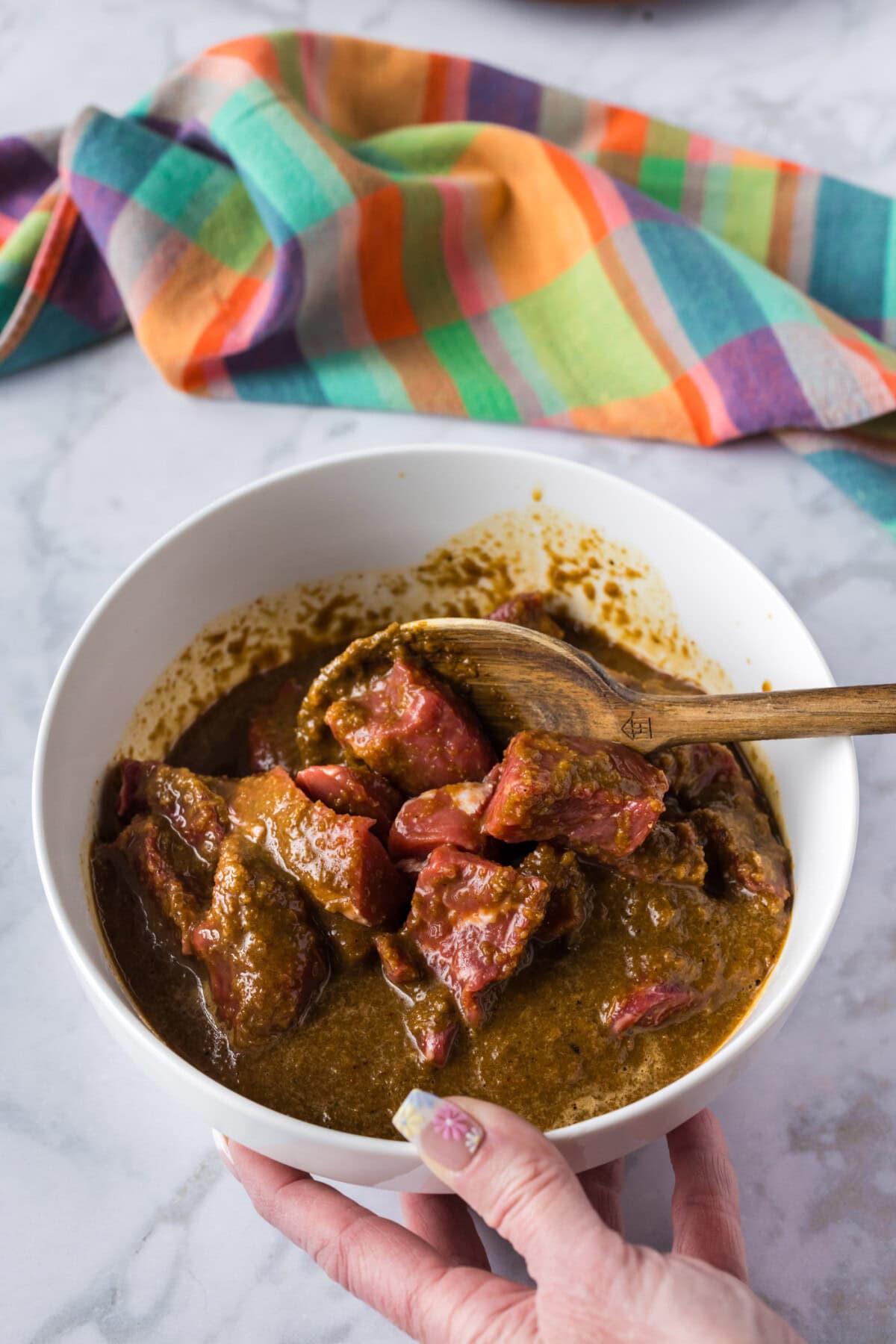 Spoon stirring steak and Bourbon Marinade in a bowl
