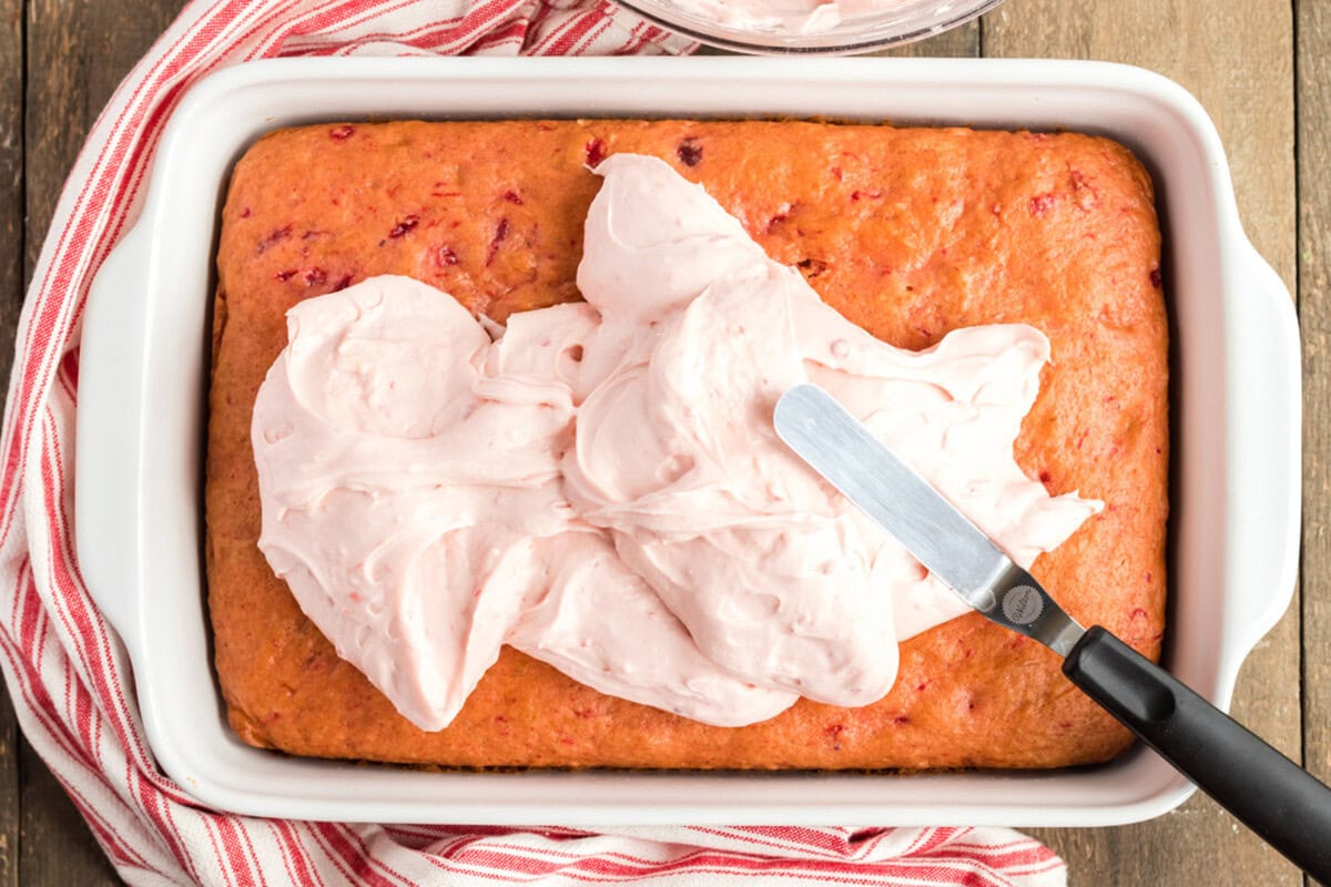 spreading frosting on to cherry cake
