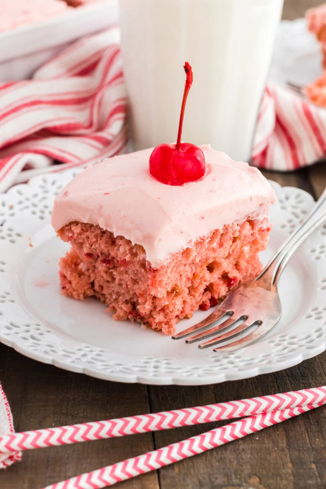 slice of cherry cake on a plate with straws in foreground