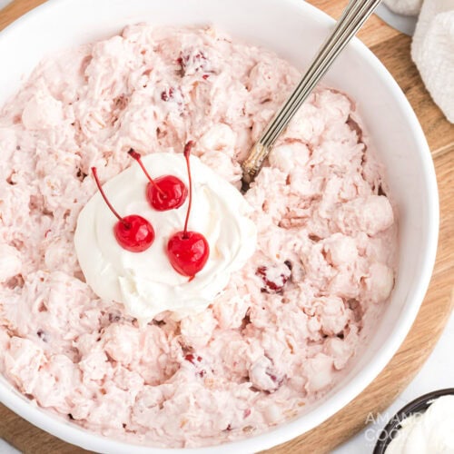 Close up photo of a bowl of Cherry Fluff topped with cool whip and maraschino cherries