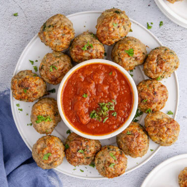 Close up photo of a plate of Chicken Meatballs with a bowl of marinara sauce