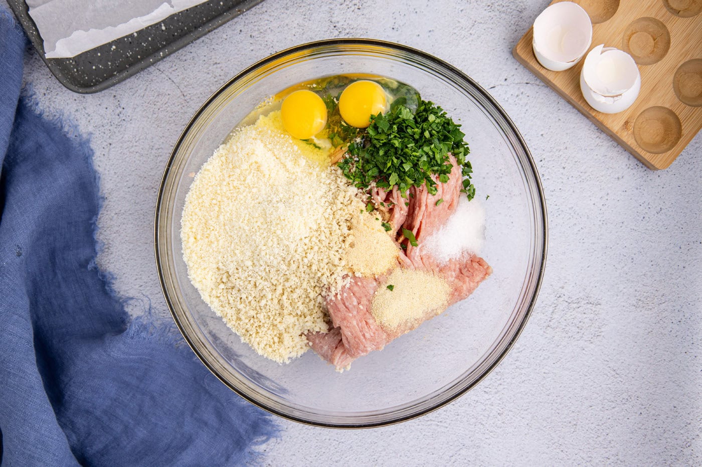 ground chicken in a bowl with egg, panko breadcrumbs, parsley, milk, and seasonings